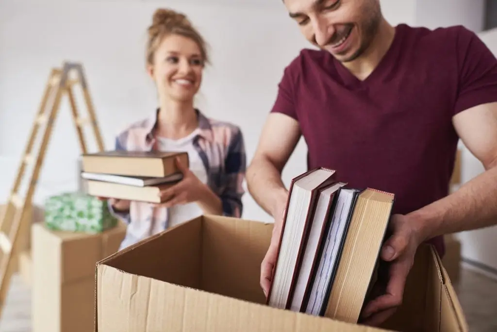 A person carefully packing books into a box.
